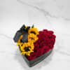 Heart-shaped box with red roses and yellow sunflowers tied with a black ribbon