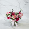 Pink and white mixed flower arrangement in a glass vase with a ribbon