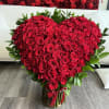 Heart-shaped bouquet of red roses with green foliage and a red ribbon
