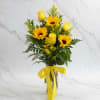 Tall arrangement of yellow sunflowers and roses in a clear vase with a yellow ribbon bow