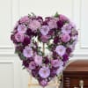 Heart-shaped purple floral tribute on an easel beside a casket