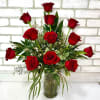 Red roses arranged in a clear glass vase with greenery