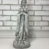 Weathered gray religious statue of a praying woman on a base