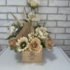 Cream and tan floral arrangement in a wooden cigar box