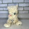 Cream teddy bear with a pink ribbon and decorative charm