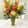 Bright mixed bouquet in a glass vase with sunflowers, roses, and lilies
