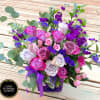 Mixed bouquet of pink and lavender roses with purple flowers in a purple vase