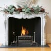 Holiday mantel garland with frosted leaves and red berries above a fireplace