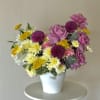 A cheerful garden-inspired arrangement featuring soft lavender roses, vibrant seasonal blooms, playful
