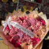 A BEAUTIFUL WRAPPED BOUQUET MIXED WITH DIFFERENT SHADES OF PINK WHITE AN
