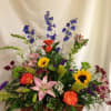 Mixed flower arrangement in a wicker basket with sunflowers, lilies, and roses