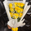 Bouquet of yellow roses with white filler flowers wrapped in white paper and tied with a yellow ribbon