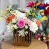 Mixed bouquet of roses, lilies, and carnations in a gold vase