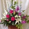 Tall mixed floral arrangement with pink roses and white lilies in a copper container