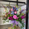 Large mixed bouquet in a glass vase with pink, purple, blue, and white flowers