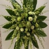 Large green floral spray with orchids and roses on a stand