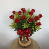 Red roses arranged in a glass vase with a red ribbon