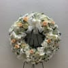 White floral wreath with peach roses and lilies on a stand