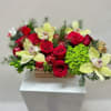 Red roses and pale yellow orchids in a low rectangular container