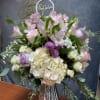 Pink and white floral arrangement in a glass vase with a Christmas topper