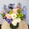 Mixed bouquet in a dark green vase with pink, purple, white, and blue flowers