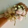 Small wrist corsage with pale pink roses and white baby's breath on gold ribbon