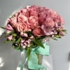 Pink rose bouquet in a glass vase with a turquoise ribbon