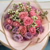 Bouquet of pink and lavender roses wrapped in pale pink paper