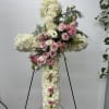 Large white floral cross with pink roses on a stand