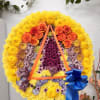 Large floral wreath with yellow, orange, and purple flowers and a blue ribbon