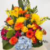 Bright mixed bouquet with roses, gerberas, lilies, and blue hydrangea in a vase