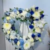 Heart-shaped floral wreath with blue, white, and yellow flowers on a stand