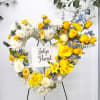 Heart-shaped floral wreath on an easel with yellow and white flowers