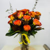 Bouquet of orange and yellow roses in a clear glass vase with a yellow ribbon