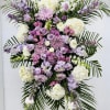 Large standing floral spray in lavender, pink, and white on a stand