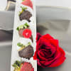 Box of chocolate-covered strawberries beside a red rose