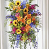 Tall standing arrangement with sunflowers, lilies, and blue flowers