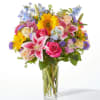 Mixed bouquet of sunflowers, roses, and lilies in a clear glass vase