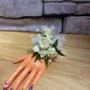 White rose wrist corsage on a mannequin hand with sheer ribbon