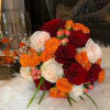 Bouquet of red, orange, and white roses with small berry accents