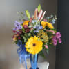 Mixed bouquet with lilies, gerbera daisies, and roses in a blue vase