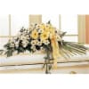 White and yellow daisy arrangement on a casket with a yellow ribbon