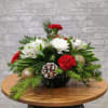 Holiday centerpiece with red carnations, white lilies, pinecones, and evergreen branches