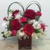 Red roses and carnations in a square glass vase with looped handles