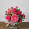 Pink mixed flower arrangement in a square glass vase with a ribbon