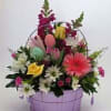 Mixed flower basket with pastel eggs in a lavender container