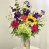 Colorful mixed bouquet in a clear glass vase with a striped ribbon