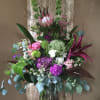 Arrangement with assorted purple and green blooms. (One side look)