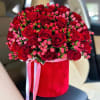 Red roses and pink berries in a red hatbox with ribbon