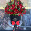 Red tulips arranged in a black hatbox with a pink bow